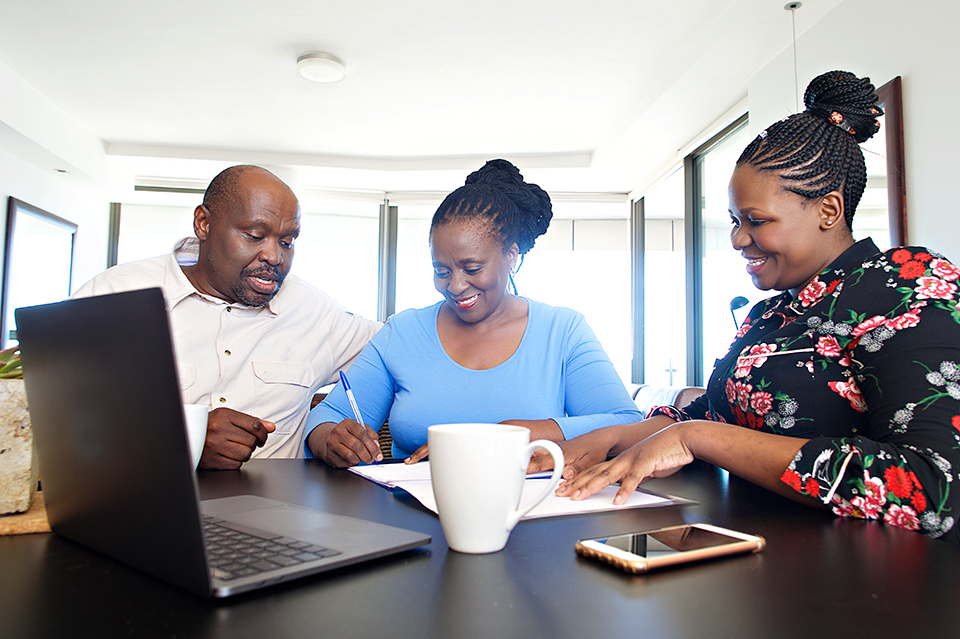 A woman giving financial advice to a senior couple in their apartment signing a document