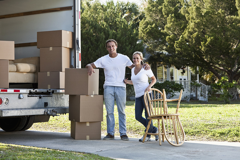 Young couple with moving van in driveway